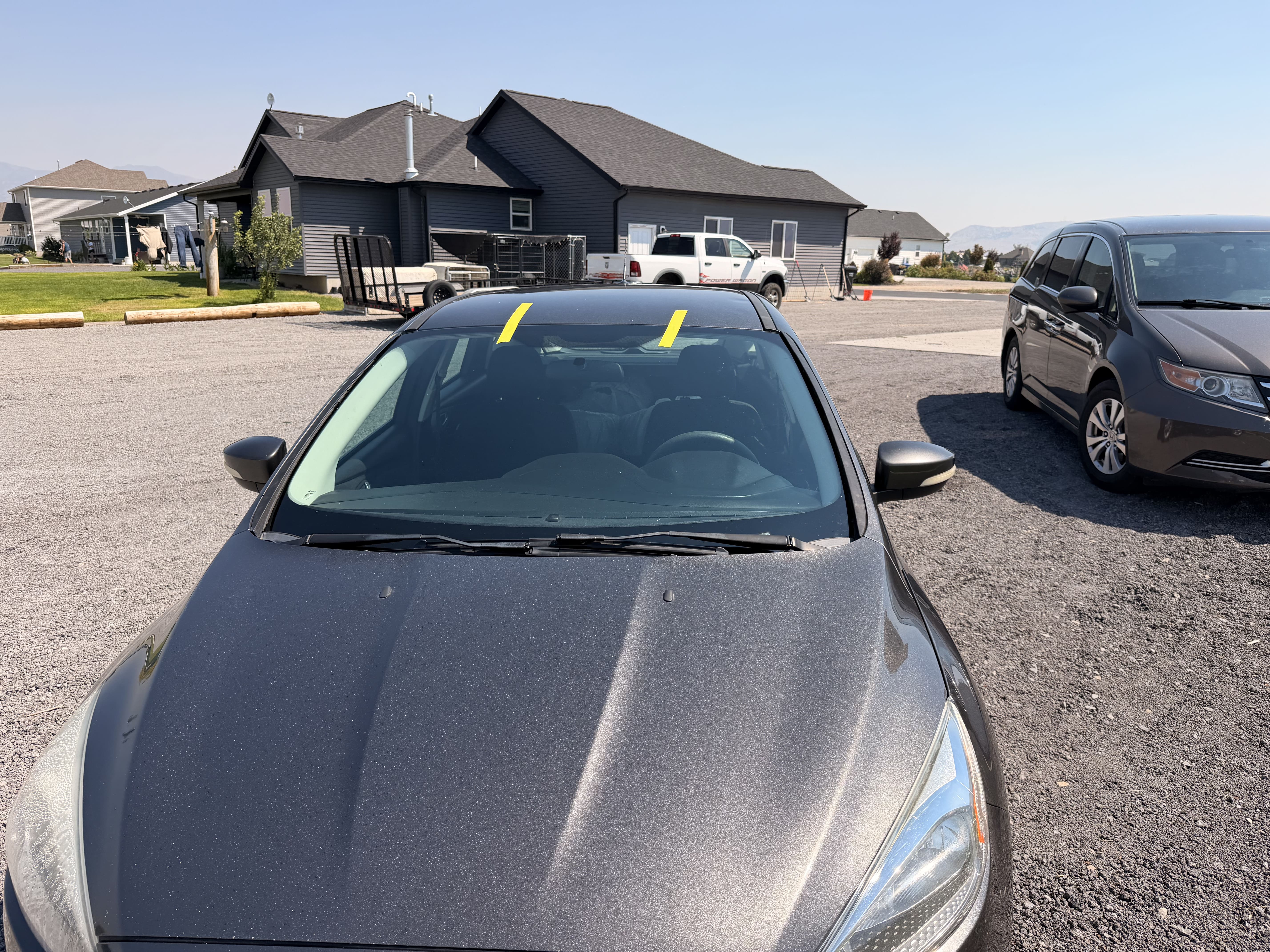 Gray hatchback with new windshield taped during cure